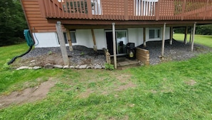 Een huis met een houten terras, een overdekte veranda en een grindpad.
