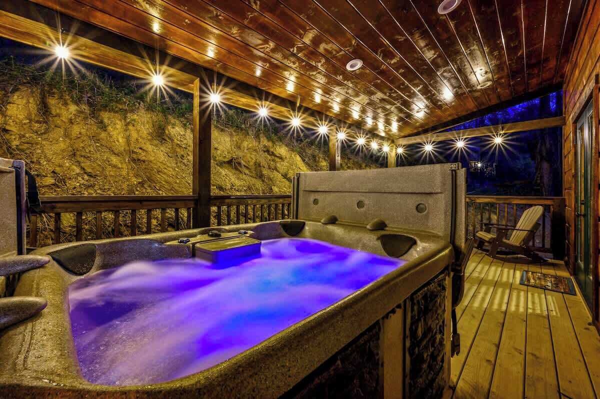 Un jacuzzi con terraza de madera y vista a una ladera rocosa.