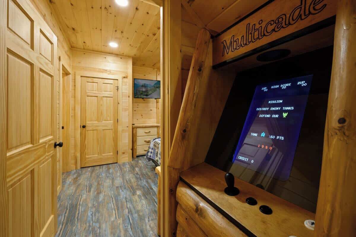A wooden interior with a wooden cabinet labeled 'Multicade' and a television screen displaying game scores.
