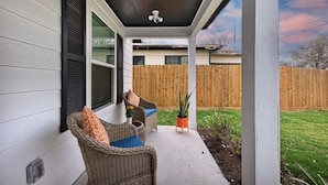 A covered porch with wicker furniture and a ceiling fan. - Howdy Holiday: Modern Family Getaway (Corpus Christi)