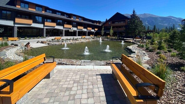 A courtyard with a fountain, benches, and a building with multiple floors and balconies. - Le Bucheron Stunning Spring Creek Luxury condo (Canmore)
