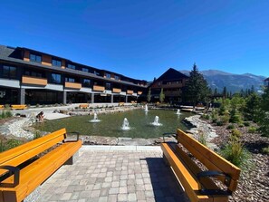 A courtyard with a fountain, benches, and a building with multiple floors and balconies.