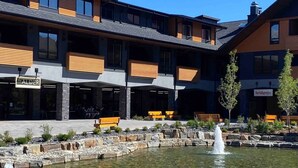A modern building with a courtyard, benches, and a water feature. - Le Bucheron Stunning Spring Creek Luxury condo (Canmore)
