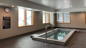 A hot tub with a metal ladder, a clock, and a sign with hot tub rules. - Le Bucheron Stunning Spring Creek Luxury condo (Canmore)