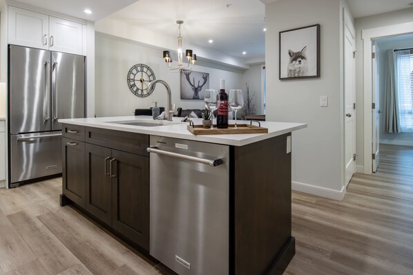 A modern kitchen with stainless steel appliances, a central island, and a clock on the wall.