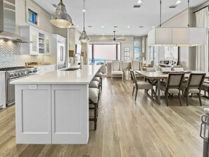 Una cocina moderna con una isla grande, armarios blancos y una zona de comedor con mesa y sillas.