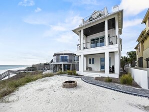 Una propiedad frente a la playa con un edificio de dos pisos, un patio cubierto y una zona de arena.