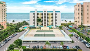 Un hotel con patio central, varios estacionamientos y vista al océano.