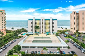 A hotel with a central courtyard, multiple parking lots, and a view of the ocean.
