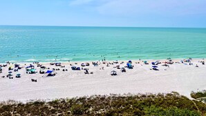 Una playa con numerosos sombrillas y tumbonas, lo que indica un lugar turístico popular.