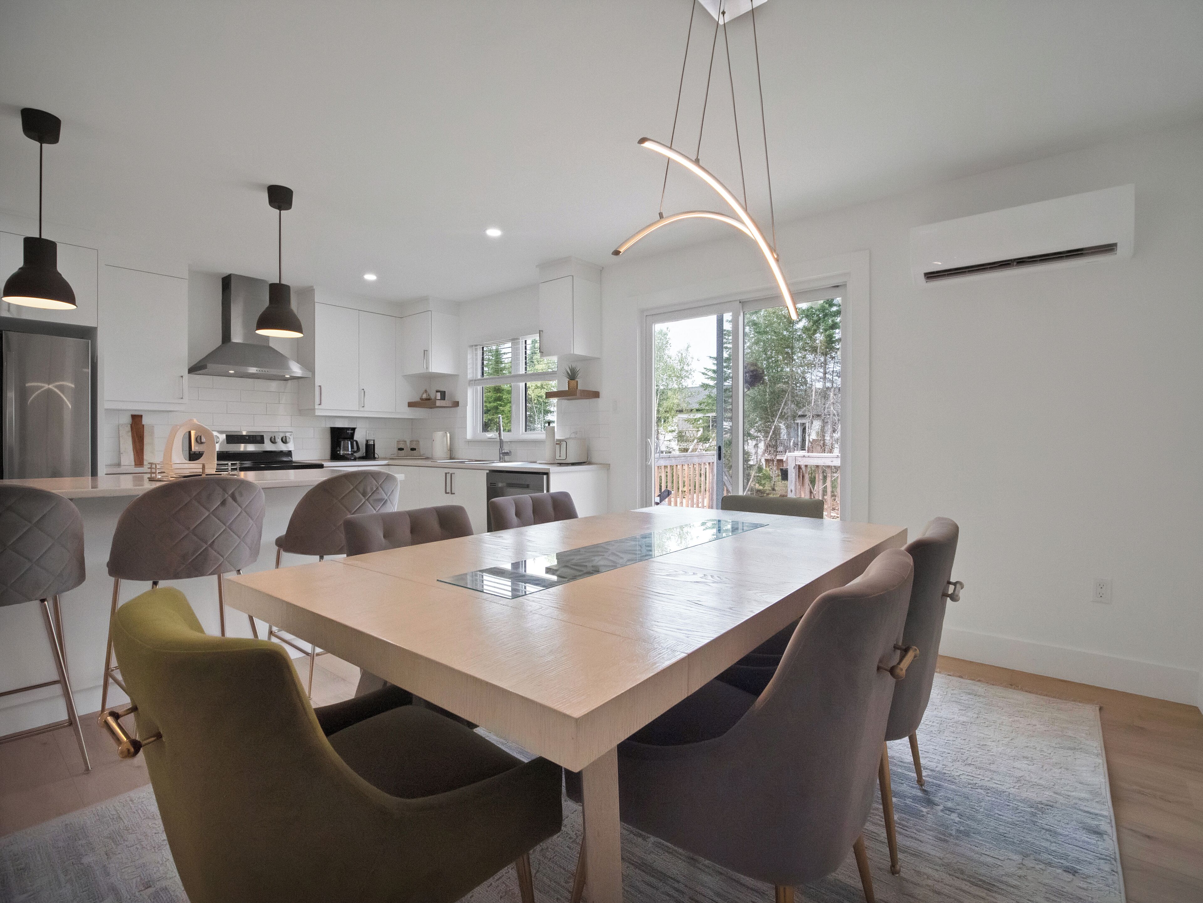 Een moderne keuken met witte kasten, een centraal eiland en hanglampen.
