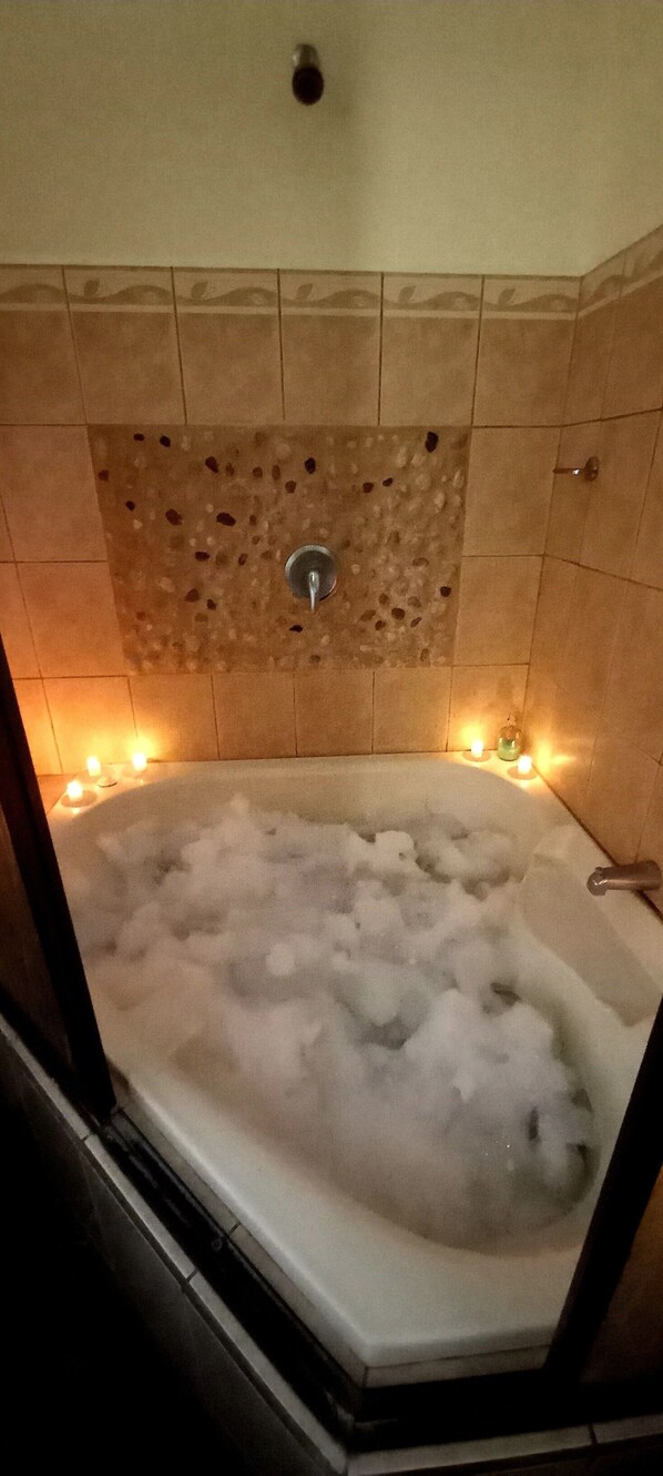 Ein Whirlpool mit gefliestem Wandbereich und Duschbrause.