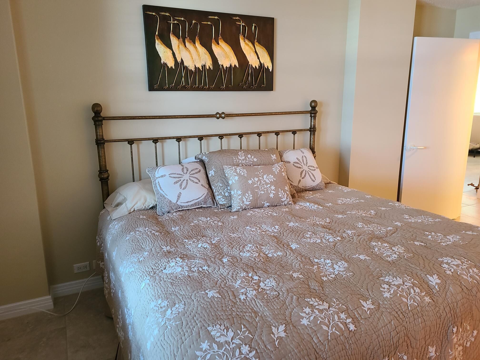 Un dormitorio con cama, cabecera y un cuadro colgado en la pared con aves.