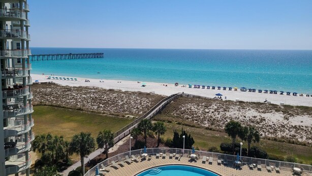 A beachfront hotel with a pool, beach umbrellas, and a pier. - 7th floor 2 bedroom 2 bath oceanfront condo at Beach Colony West. (Navarre)