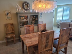 A dining area with a wooden table and chairs, a decorative chandelier, and a cabinet with glass doors displaying various items.