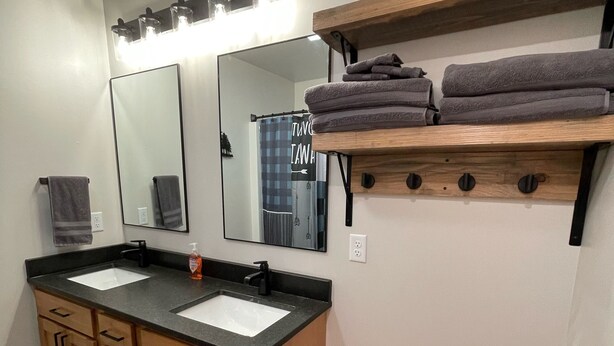 A bathroom with two sinks, wooden cabinets, a mirror, and a towel rack.