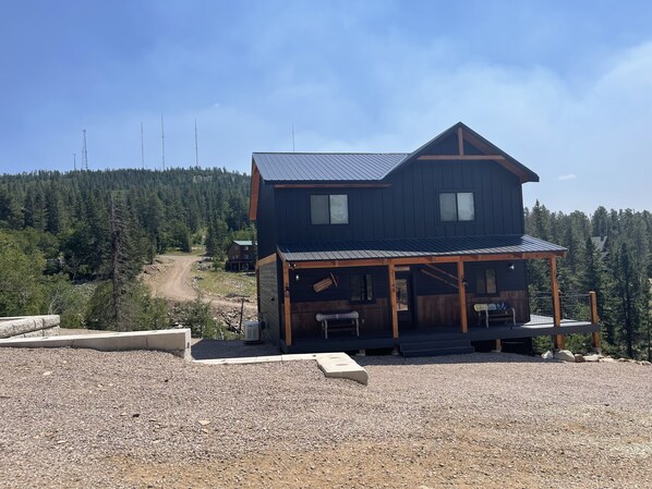 A two-story cabin with a metal roof, a porch, and a gravel driveway. - NEW Cabin in Terry Peak!  Views, Space, and lots more!  Sleeps 14, NO bunk beds! (Lead)