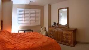 A bedroom with a large bed, a dresser, a mirror, and a window with blinds. - #1 Large sunny room perfect for relaxing (St. George)
