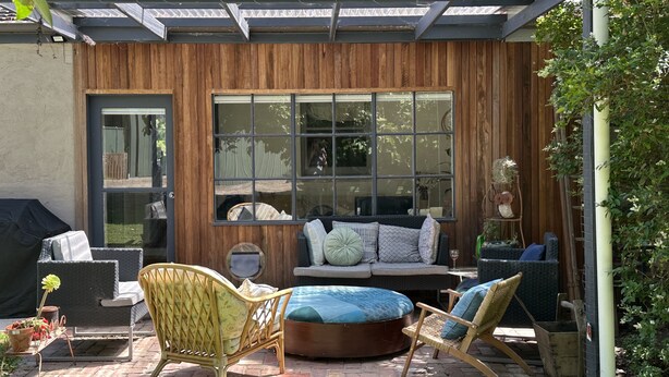 A patio with a wooden wall, a large window, wicker furniture, and a grill. - Yea Fig Tree House. Three bedroom plus study comfortable family home. (Yea)