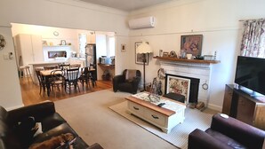 A living room with a fireplace, a television, and a dining area with chairs and a table. - Yea Fig Tree House. Three bedroom plus study comfortable family home. (Yea)