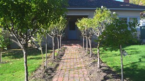 A pathway leading to a house with a brick entrance, surrounded by young trees and a grassy lawn. - Yea Fig Tree House. Three bedroom plus study comfortable family home. (Yea)