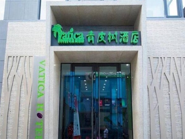 Entrada de hotel con un letrero en idioma extranjero, puerta de cristal y fachada con textura.