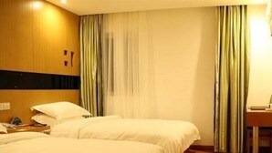 A hotel room with two beds, a wooden headboard, a desk with a chair, and a window with curtains. - Vatica Chaoyang the East of Railway Station Xinhua Road Hotel (Chaoyang)