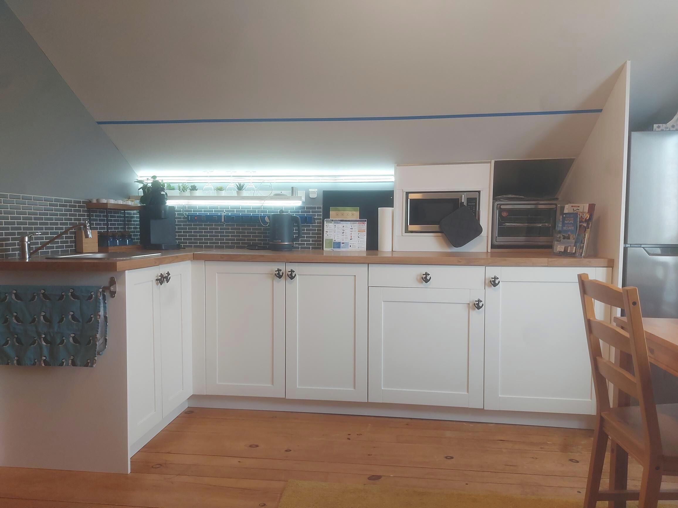 A kitchen with white cabinets, a wooden countertop, a microwave, and a refrigerator.