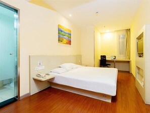 Une chambre d’hôtel avec un lit, une table de chevet, un bureau, une chaise et un tableau au mur.