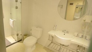 Une salle de bain moderne avec une douche à parois de verre, des toilettes, un lavabo avec un miroir et un porte-serviettes.