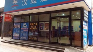 Un hôtel à la façade bleue, doté de grandes fenêtres en verre et de nombreuses enseignes annonçant des soldes et des promotions.