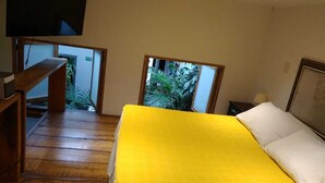 A room with a bed, a wooden desk, and a TV mounted on the wall.