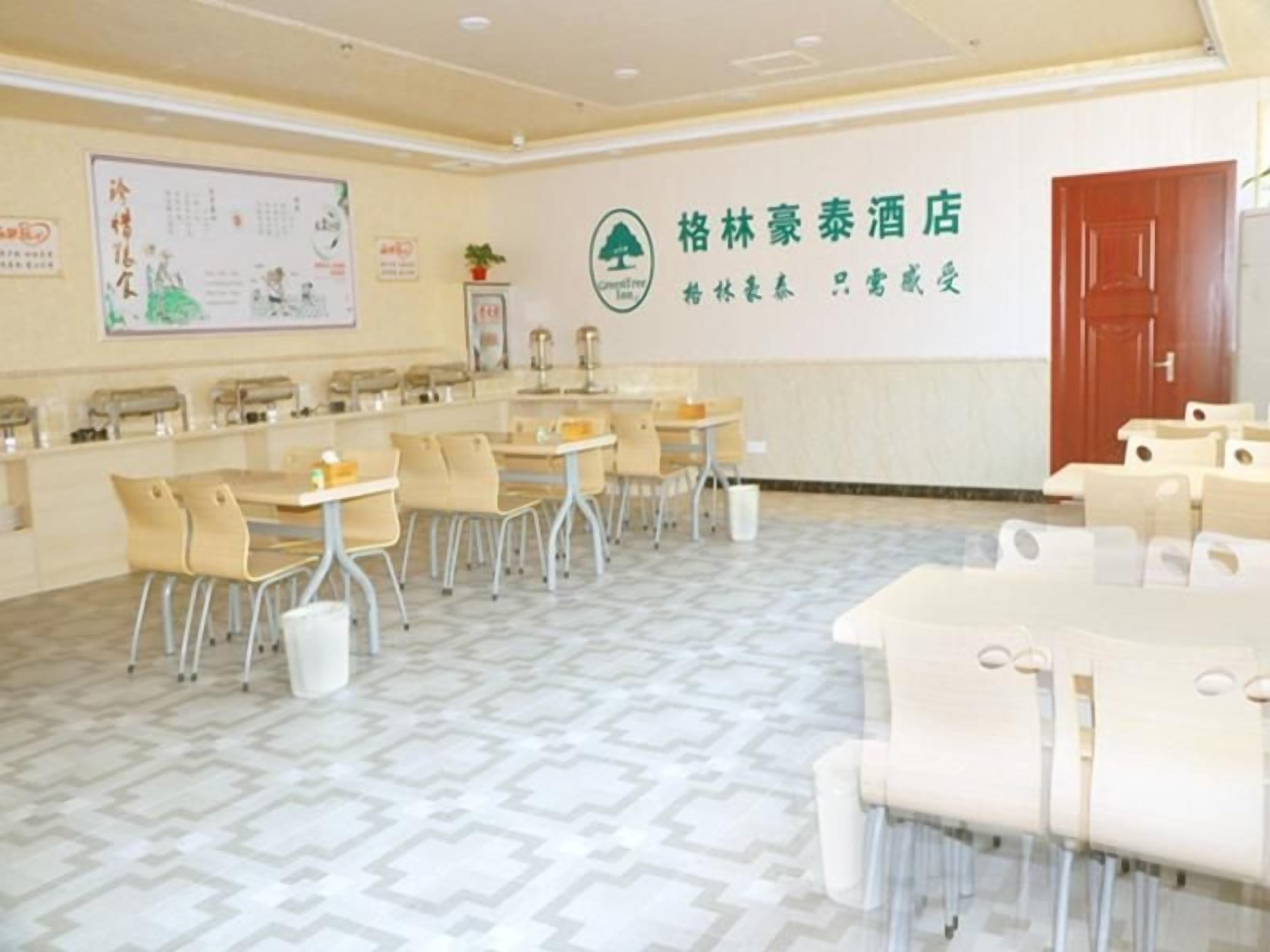 A hotel room with a reception desk, several tables and chairs, a large wall with a logo, and a patterned floor.