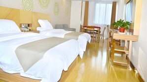 Ett hotellrum med två sängar, ett skrivbord, en stol och en krukväxt.