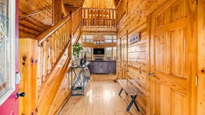 L’intérieur d’une cabane en bois comprend un escalier central, un coin cuisine et un banc.