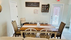 Un comedor con una mesa de madera, sillas blancas y un cartel que dice 'Hello and welcome'.