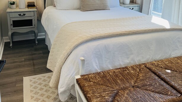 Un dormitorio con una cama grande, dos mesitas de noche, un espejo y una ventana con cortinas.