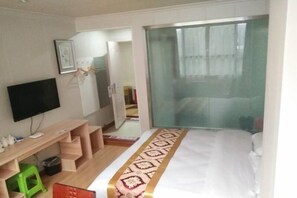 A hotel room with a bed, a TV, a desk, and a window with curtains. - Shell Hotel Chongqing Chengkouxian Branch (Chongqing)