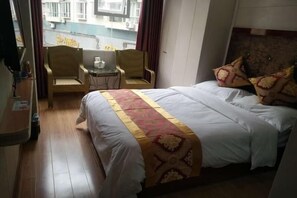 A hotel room with a bed, two chairs, a small table, and a view of the outside. - Shell Hotel Chongqing Chengkouxian Branch (Chongqing)