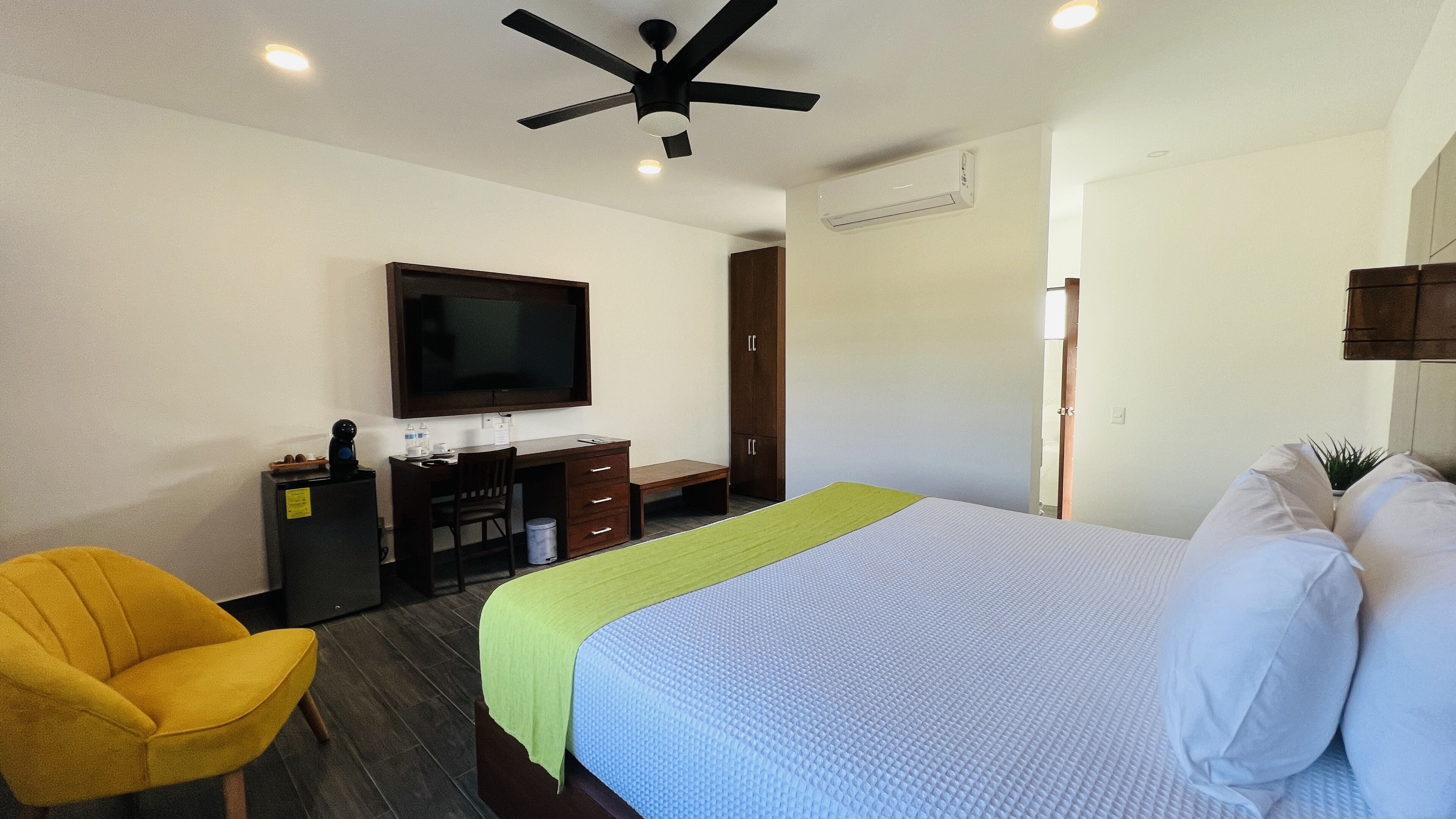 Una habitación de hotel con cama, escritorio, silla, televisor y armario.