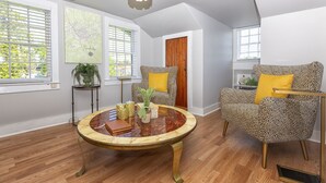 Una habitación con una mesa redonda de mármol, sillas de estampado de leopardo, una puerta de madera y un mapa en la pared.