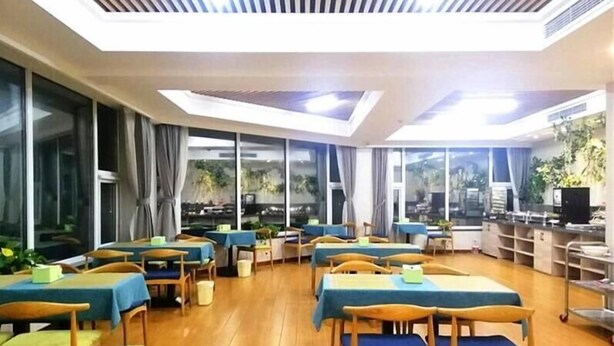 Un comedor con mesas y sillas, ventanas amplias y un techo con ventilación.