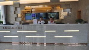 Una recepción en el GreenTree Inn con un diseño moderno, una amplia pantalla digital y una estética limpia y minimalista.