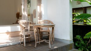 A room with a bed, a wooden table, two chairs, and a potted plant. - Suweta Homestay by Supala (Ubud)