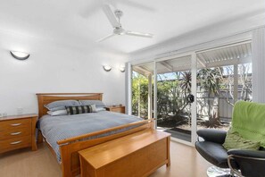 Relax in this serene bedroom with a comfortable bed, nightstand, and bench, offering a peaceful retreat with a view of the surrounding trees.