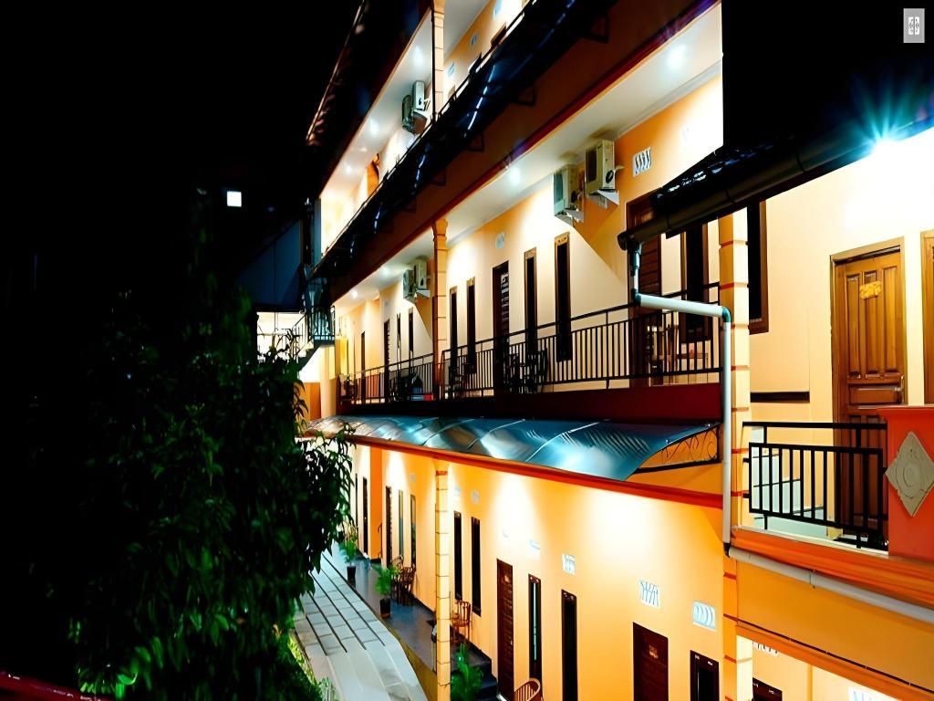 Un hotel de varios pisos con balcones, unidades de aire acondicionado y una escalera.