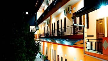 Un hotel de varios pisos con balcones, unidades de aire acondicionado y una escalera.