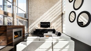 Ein modernes Wohnzimmer mit Kamin, einem Ecksofa und einem großen Fenster mit Blick auf die Stadt.