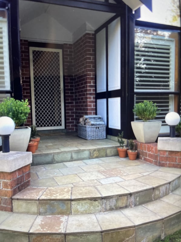 Stunning entrance with a brick and stonework facade, flanked by potted plants.