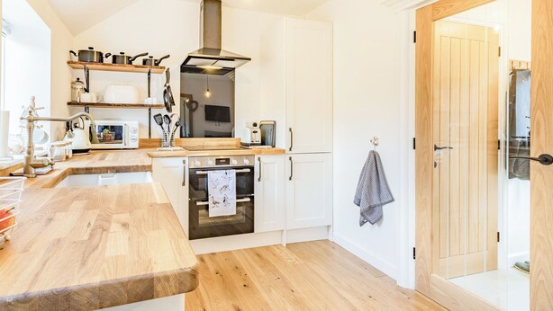 A modern kitchen with wooden countertops, a built-in oven, and a hanging light fixture.